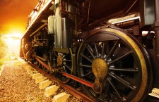 iron wheels of stream engine locomotive train on railways track perspective to golden light forward use for old and classic period land transport and retro vintage style background